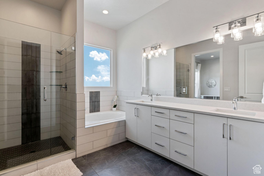 Full bathroom with a shower stall, double vanity, a bath, and a sink