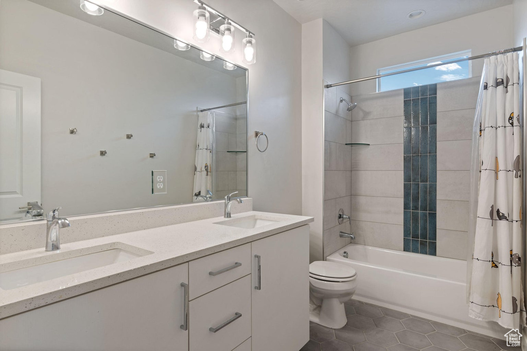 Bathroom featuring shower / bath combo with shower curtain, a sink, toilet, and tile patterned flooring