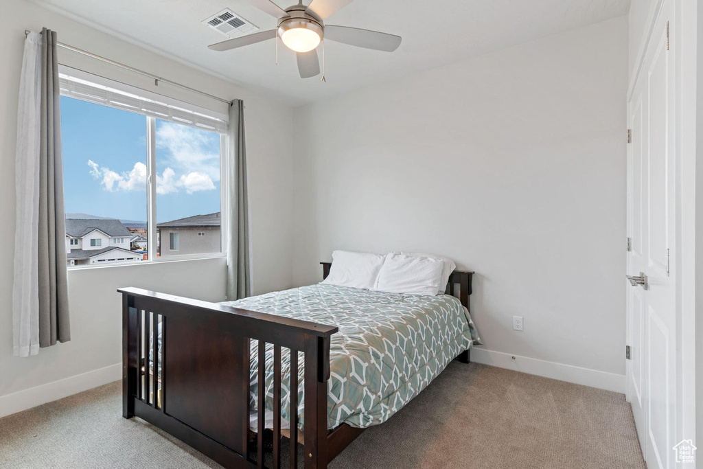 Carpeted bedroom with a ceiling fan, baseboards, and visible vents
