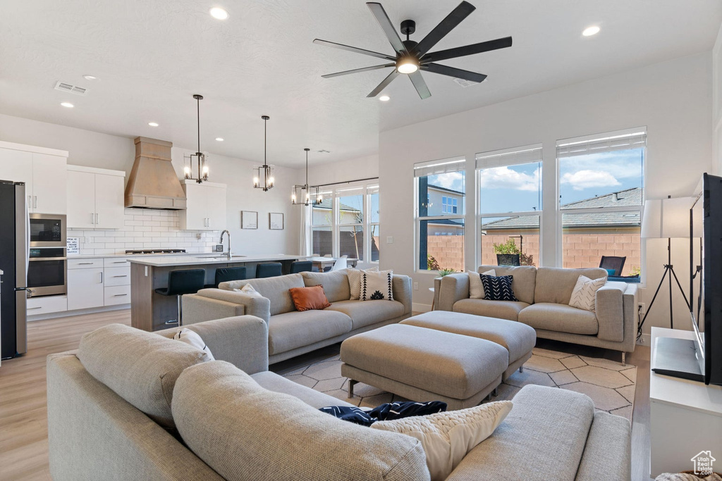 Living room featuring visible vents, light wood-type flooring, recessed lighting, and ceiling fan with notable chandelier