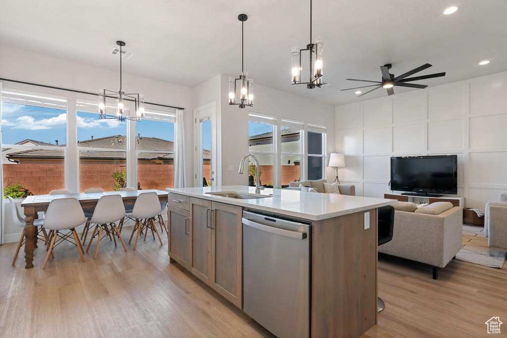 Kitchen featuring light countertops, a sink, dishwasher, open floor plan, and light wood-style floors