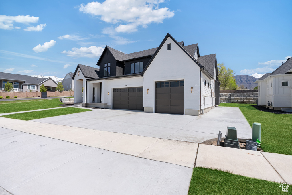 Modern inspired farmhouse with fence, an attached garage, driveway, and a front yard