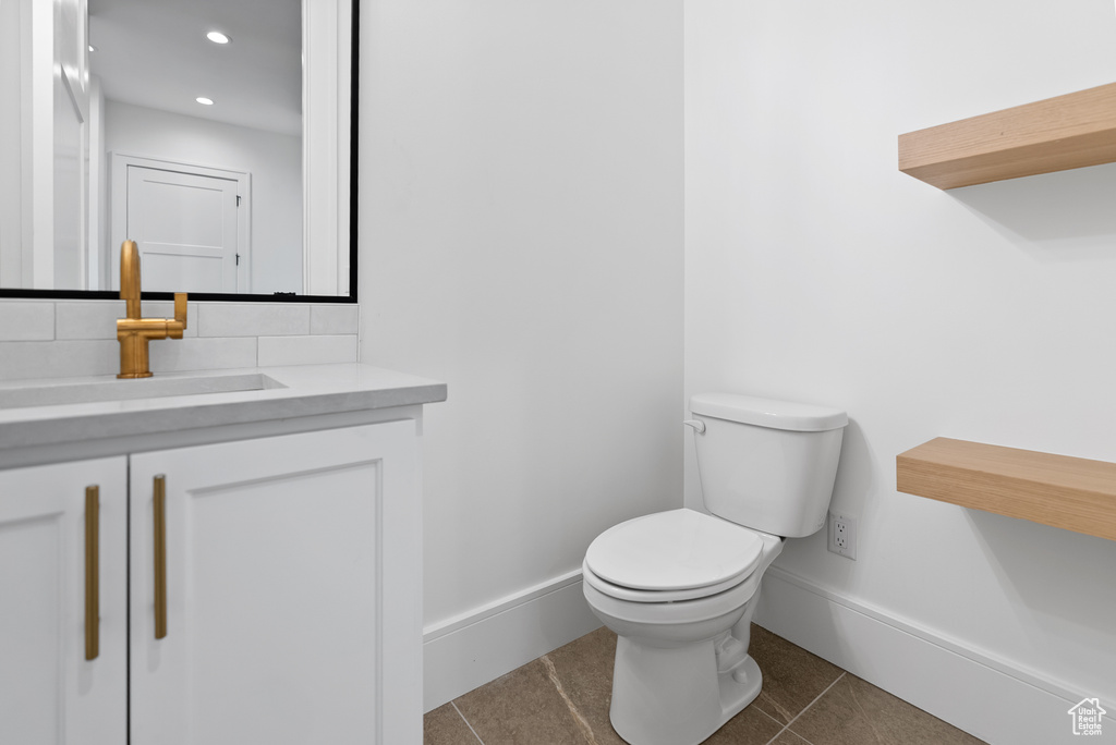 Half bathroom with tile patterned flooring, vanity, baseboards, toilet, and recessed lighting