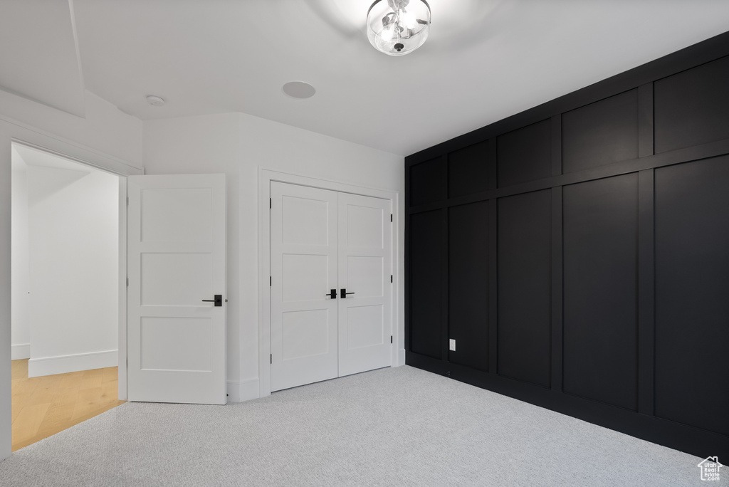 Unfurnished bedroom with baseboards, light carpet, and a closet