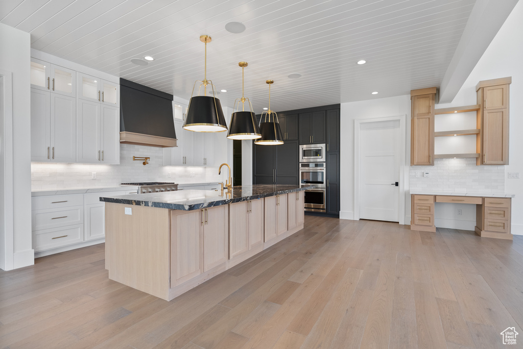 Kitchen featuring open shelves, a spacious island, tasteful backsplash, light wood finished floors, and stainless steel appliances