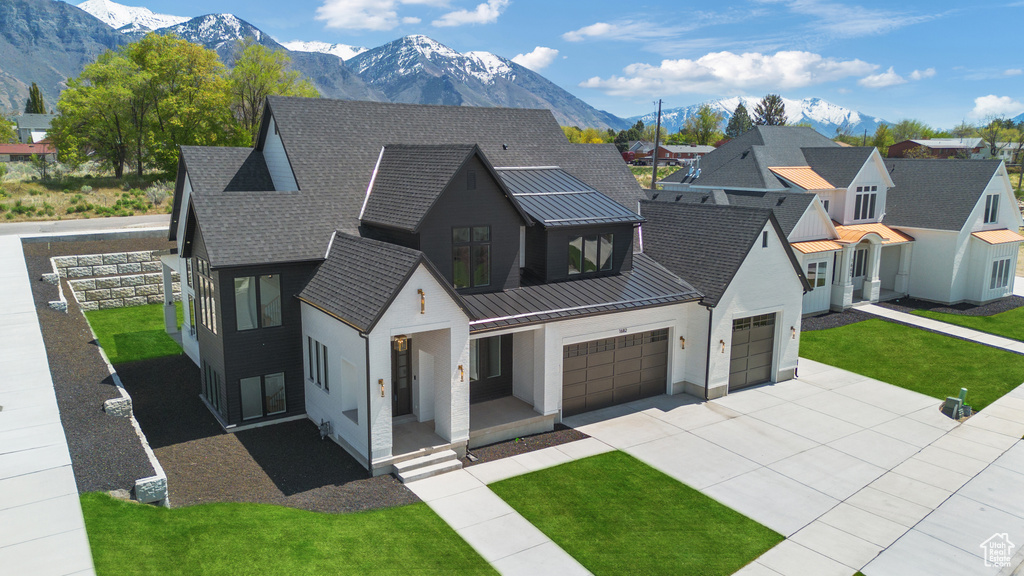 Modern inspired farmhouse featuring covered porch, a front yard, a mountain view, concrete driveway, and stucco siding