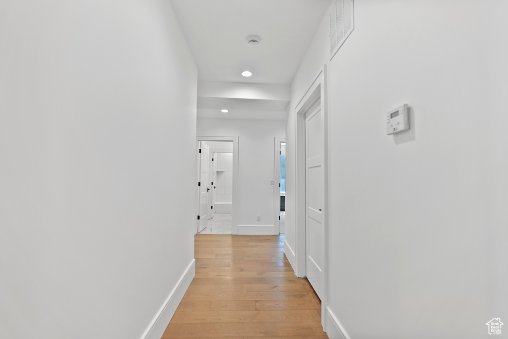 Hallway with light wood-style floors, recessed lighting, baseboards, and visible vents