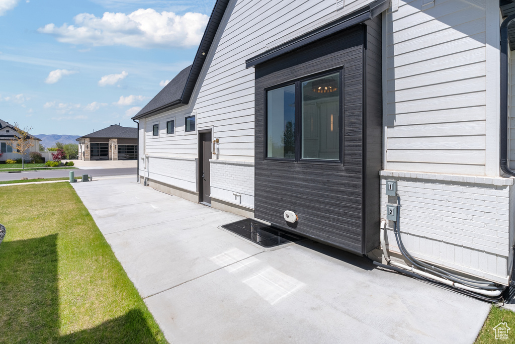 View of property exterior featuring a yard, a patio, and a mountain view