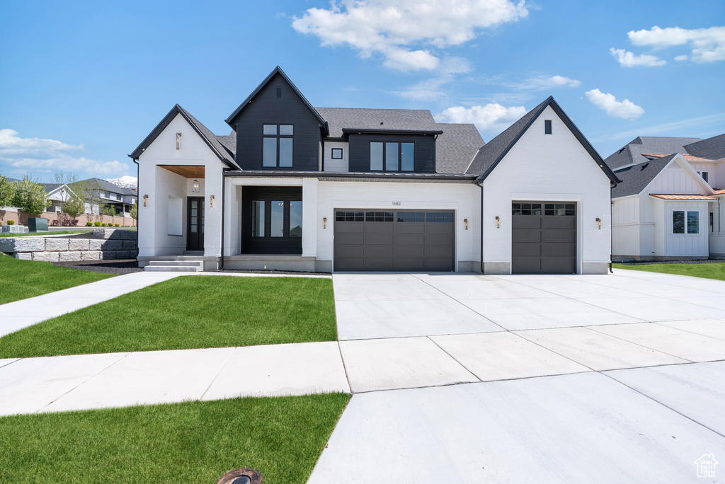 Modern farmhouse style home with an attached garage, driveway, and a front lawn