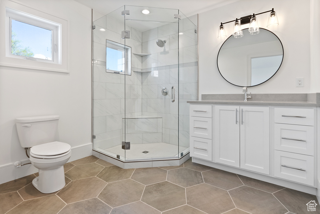 Full bathroom featuring a shower stall, vanity, tile patterned floors, baseboards, and toilet