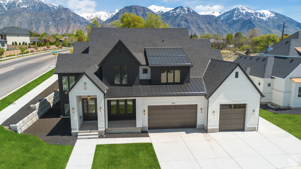 View of front of house with a garage, a mountain view, concrete driveway, a standing seam roof, and metal roof