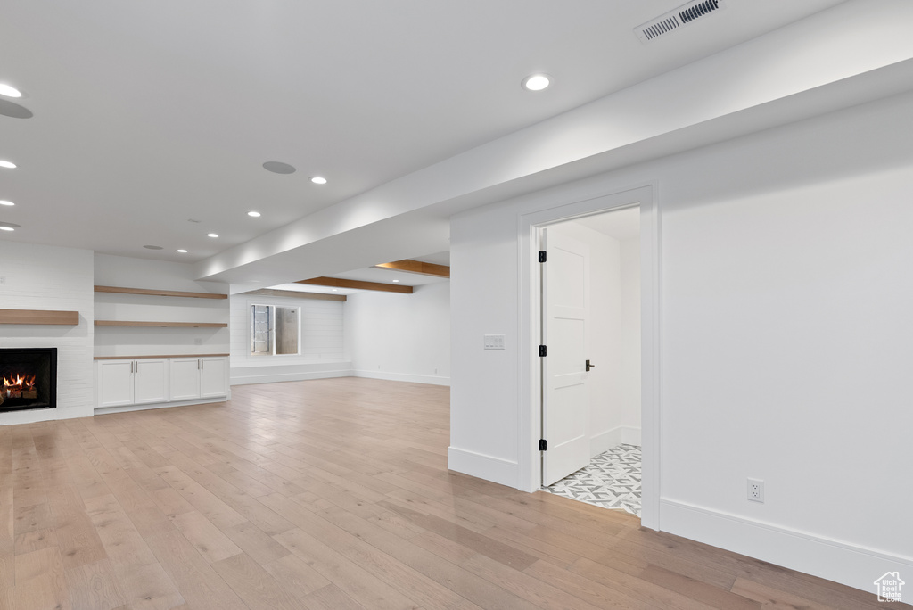 Basement with visible vents, baseboards, recessed lighting, a large fireplace, and light wood finished floors