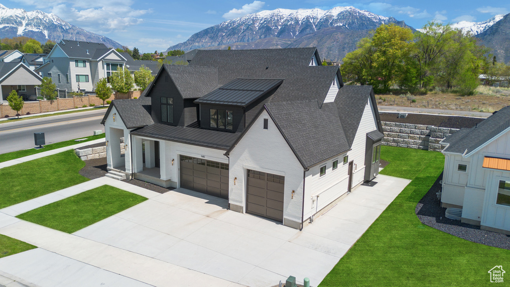 View of front of home featuring a mountain view, a shingled roof, concrete driveway, and a front yard