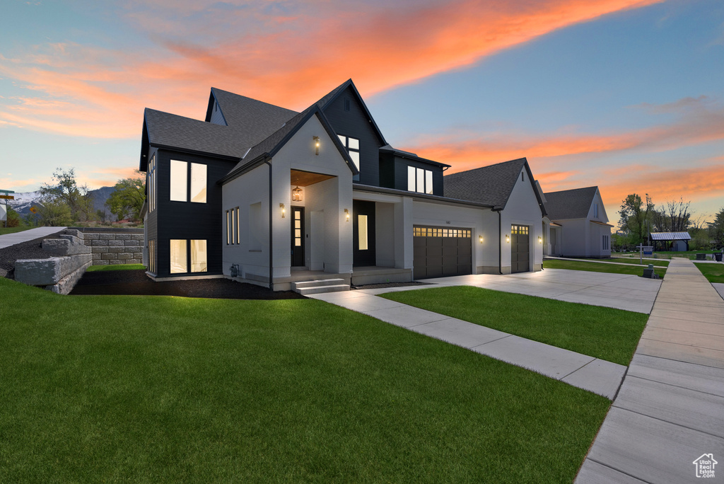 Modern farmhouse style home featuring a garage, stucco siding, a lawn, and driveway