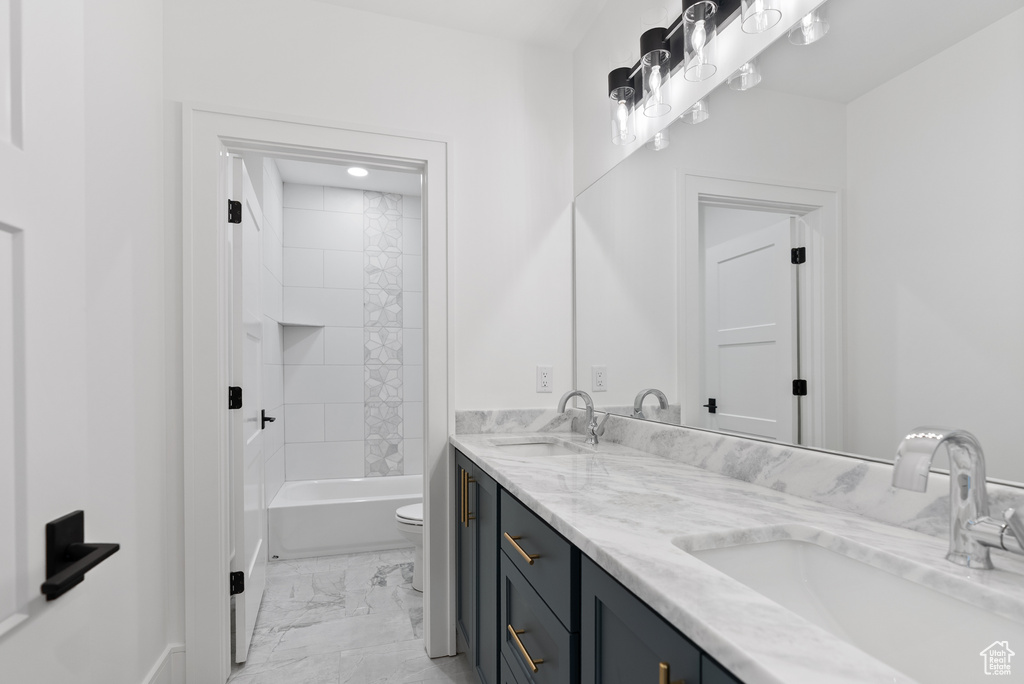 Full bath featuring double vanity, a sink, marble finish floor, and toilet