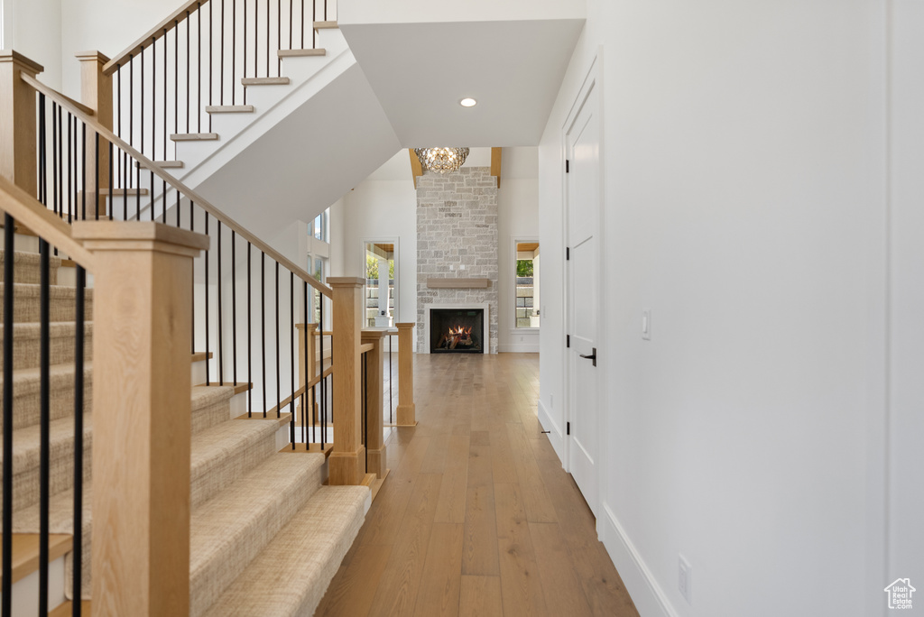 Interior space with a large fireplace, baseboards, wood-type flooring, a notable chandelier, and recessed lighting