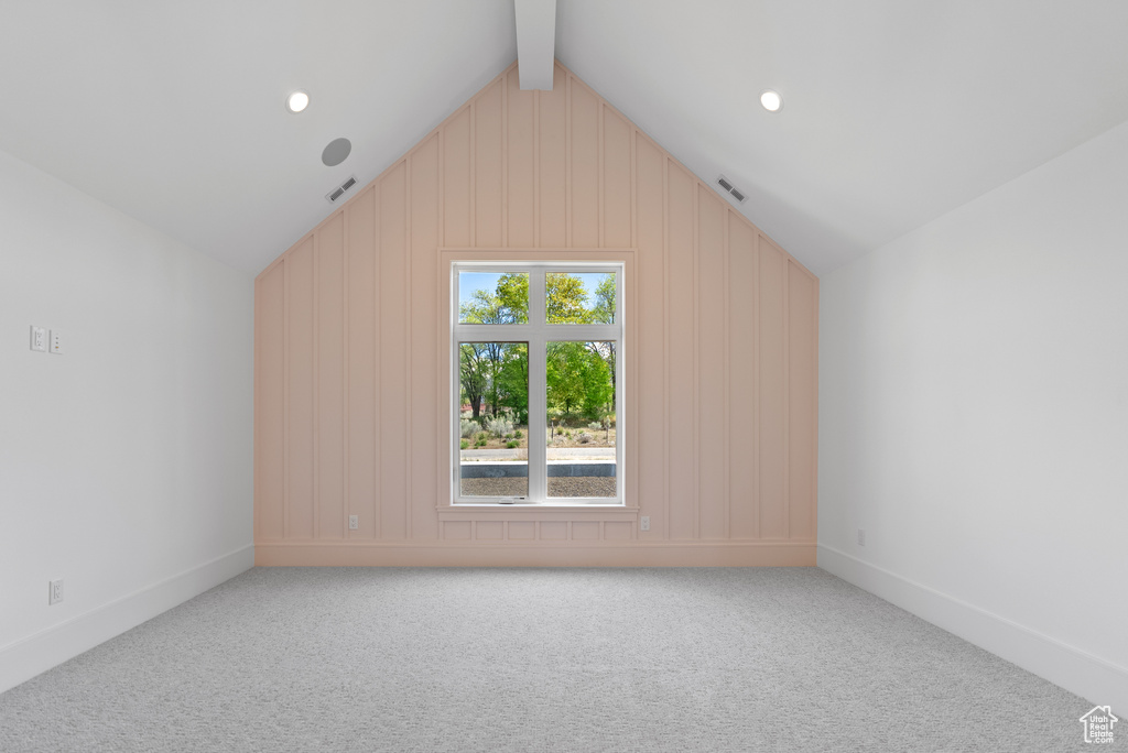 Additional living space featuring lofted ceiling with beams, carpet, and visible vents