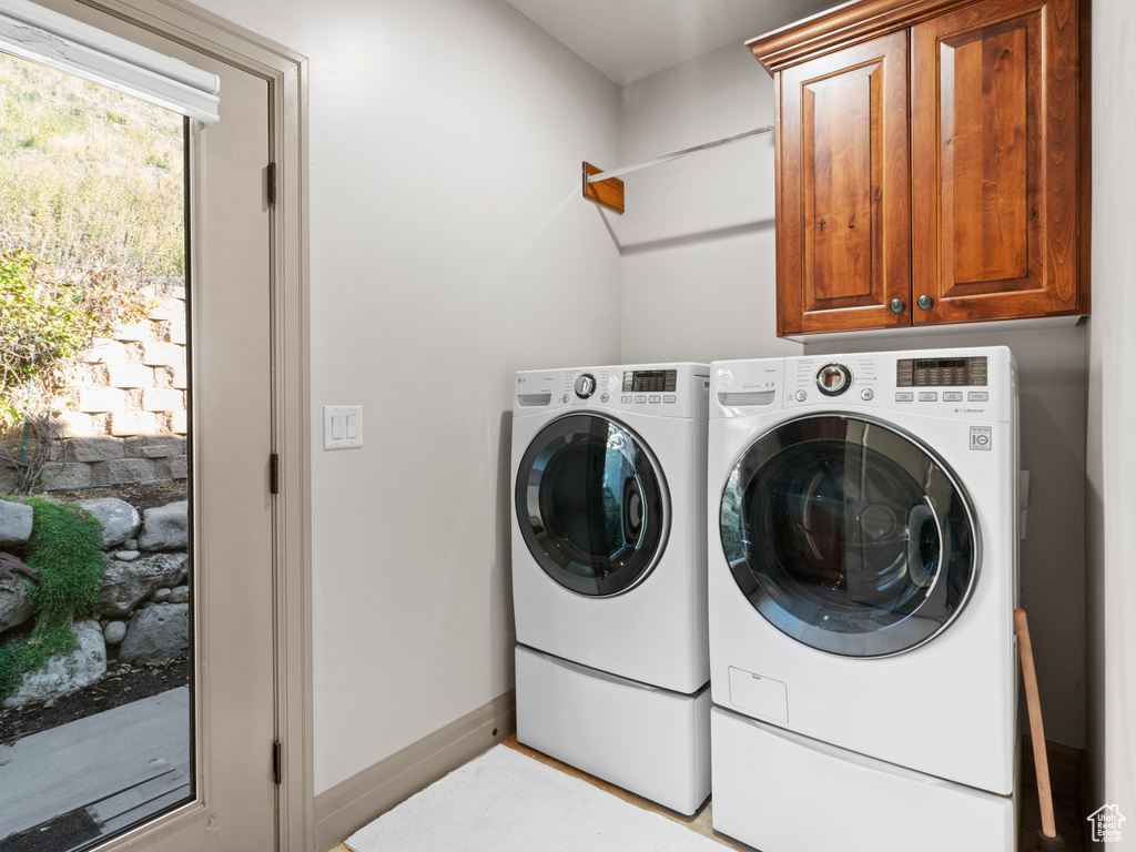 Washroom featuring cabinet space, baseboards, and washing machine and dryer