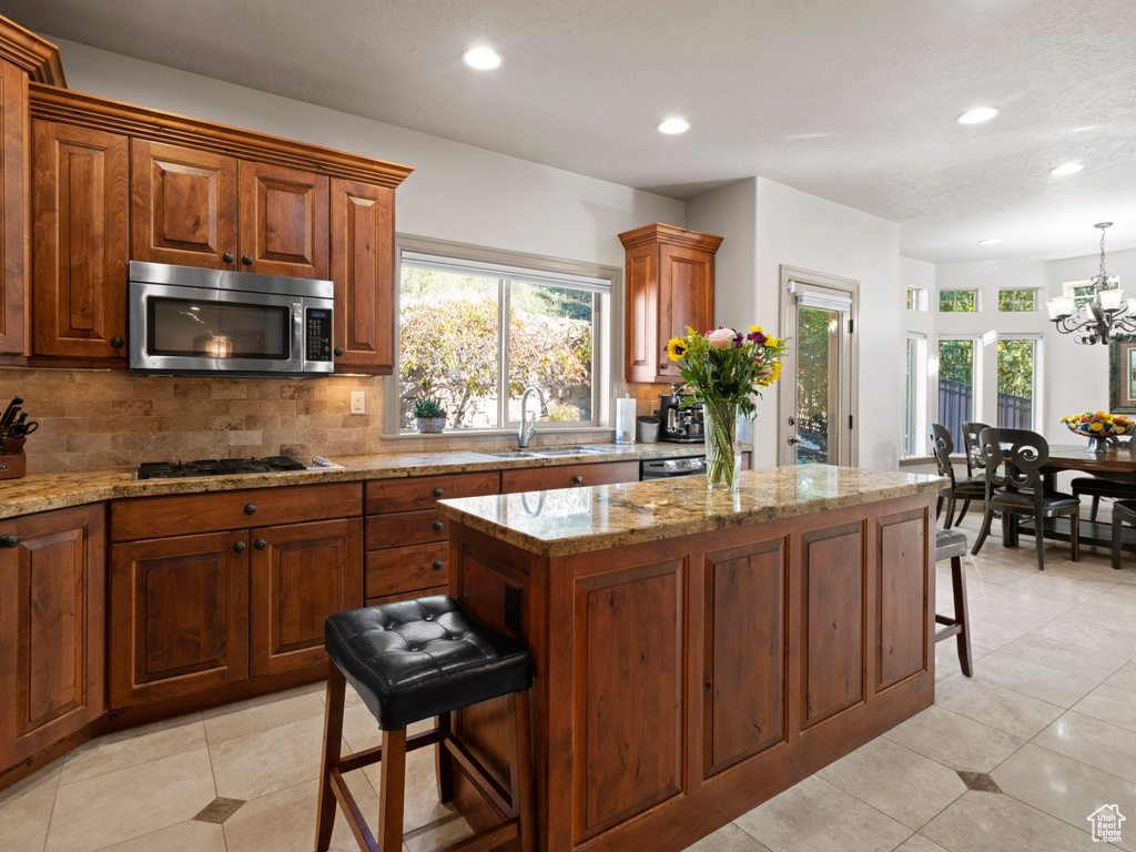 Kitchen with gas cooktop, a breakfast bar, stainless steel microwave, a sink, and decorative backsplash