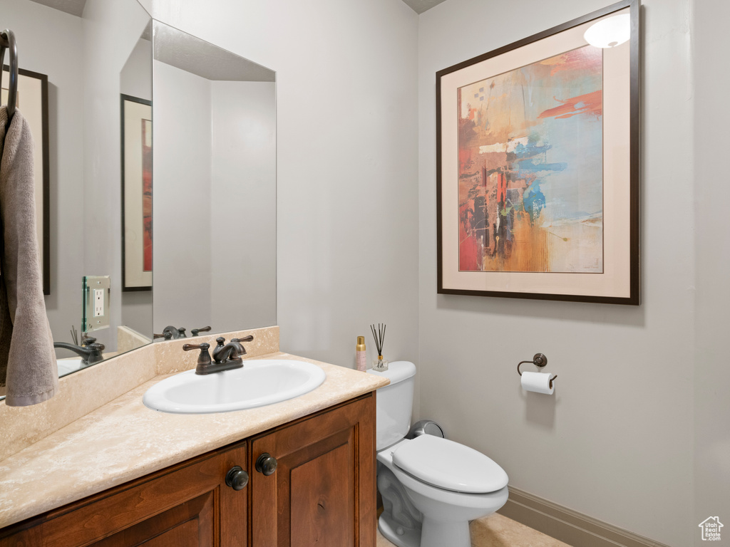 Half bath with vanity, baseboards, and toilet