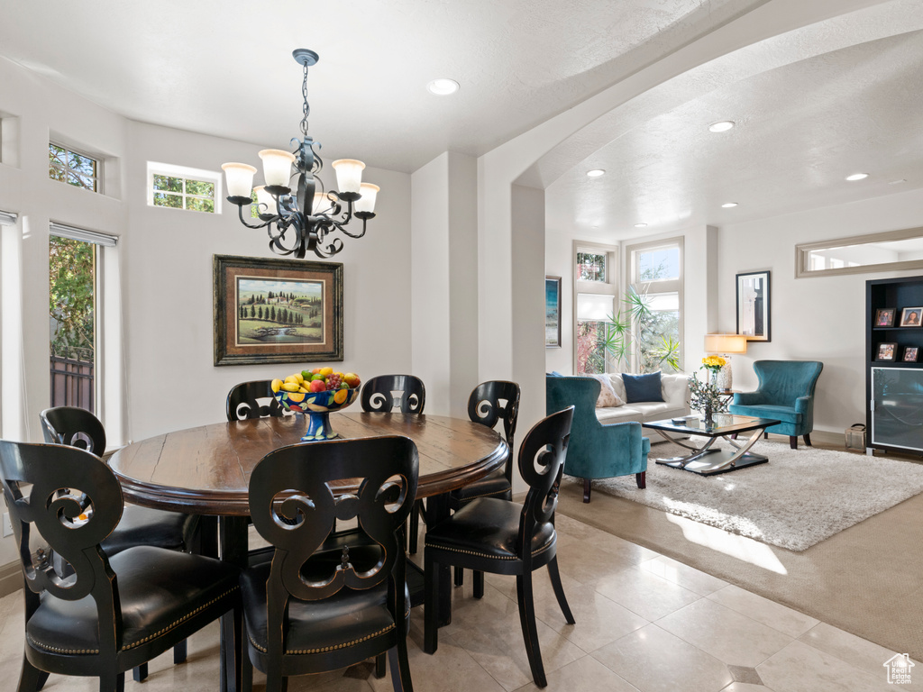 Dining area with light tile patterned floors, recessed lighting, arched walkways, and an inviting chandelier