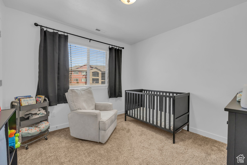 Carpeted bedroom with a nursery area, visible vents, and baseboards