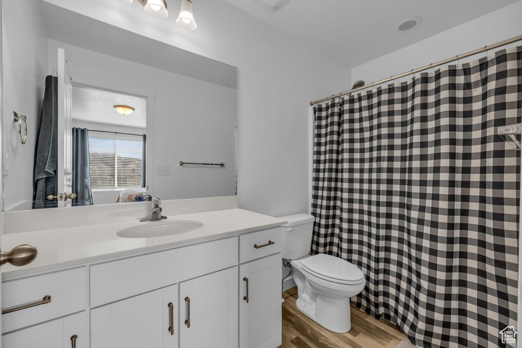 Full bathroom with ensuite bathroom, a shower with shower curtain, toilet, vanity, and wood finished floors