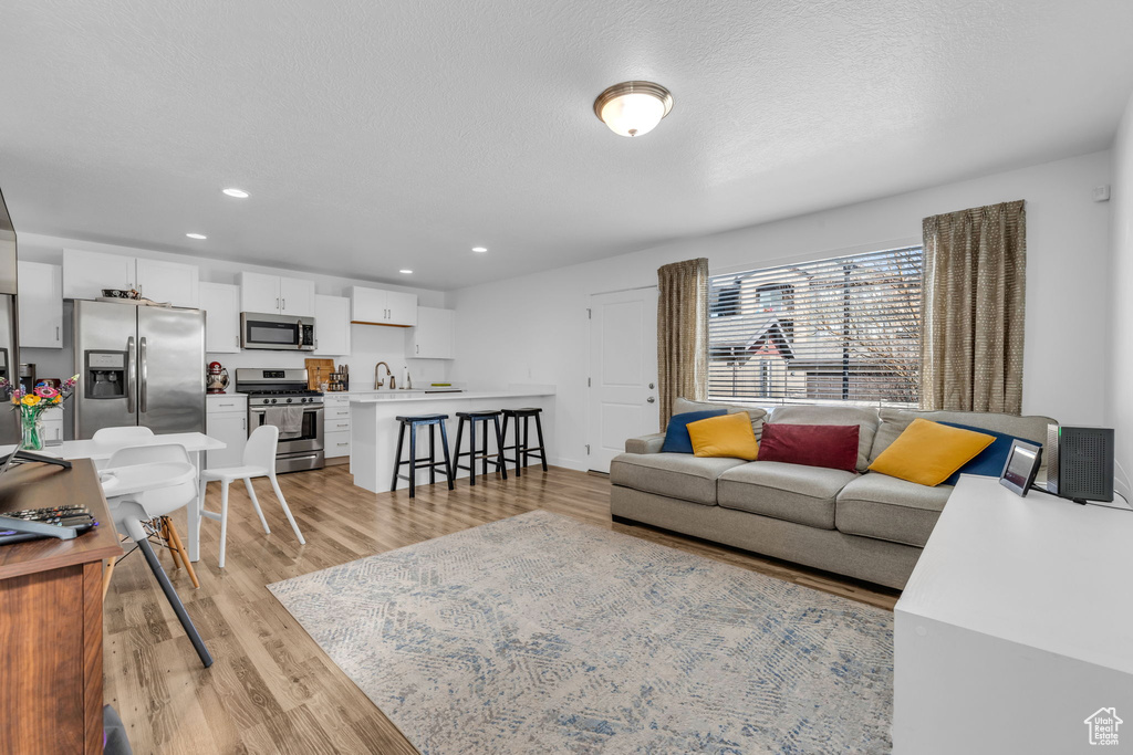 Living room featuring light wood-type flooring, recessed lighting, and a textured ceiling