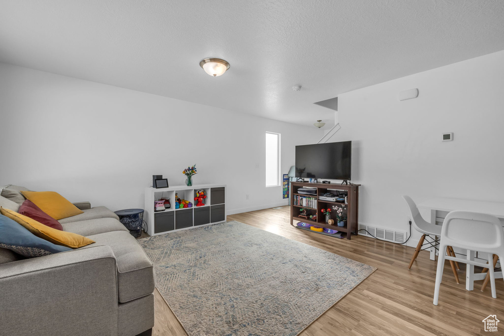 Living room featuring visible vents, light wood-type flooring, and baseboards