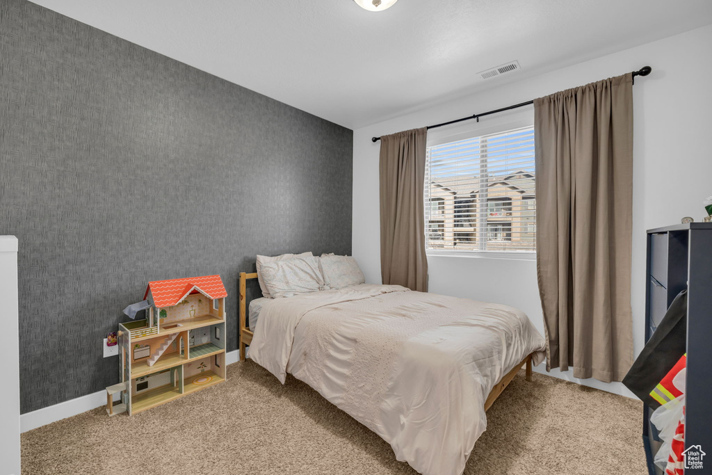 Carpeted bedroom with visible vents, baseboards, an accent wall, and wallpapered walls