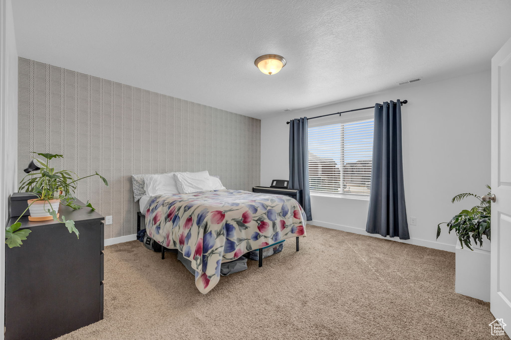 Bedroom with carpet floors, baseboards, visible vents, and wallpapered walls