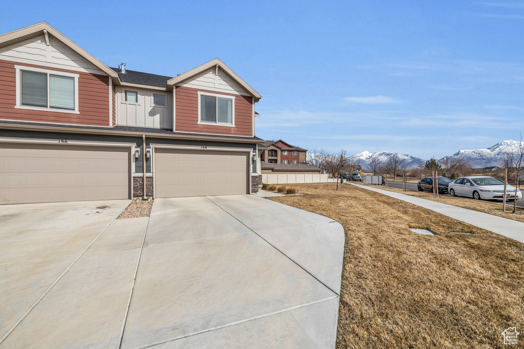 View of front of house featuring a garage, driveway, stone siding, and a mountain view