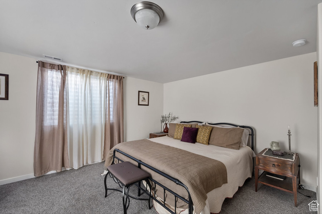 Carpeted bedroom featuring baseboards and visible vents