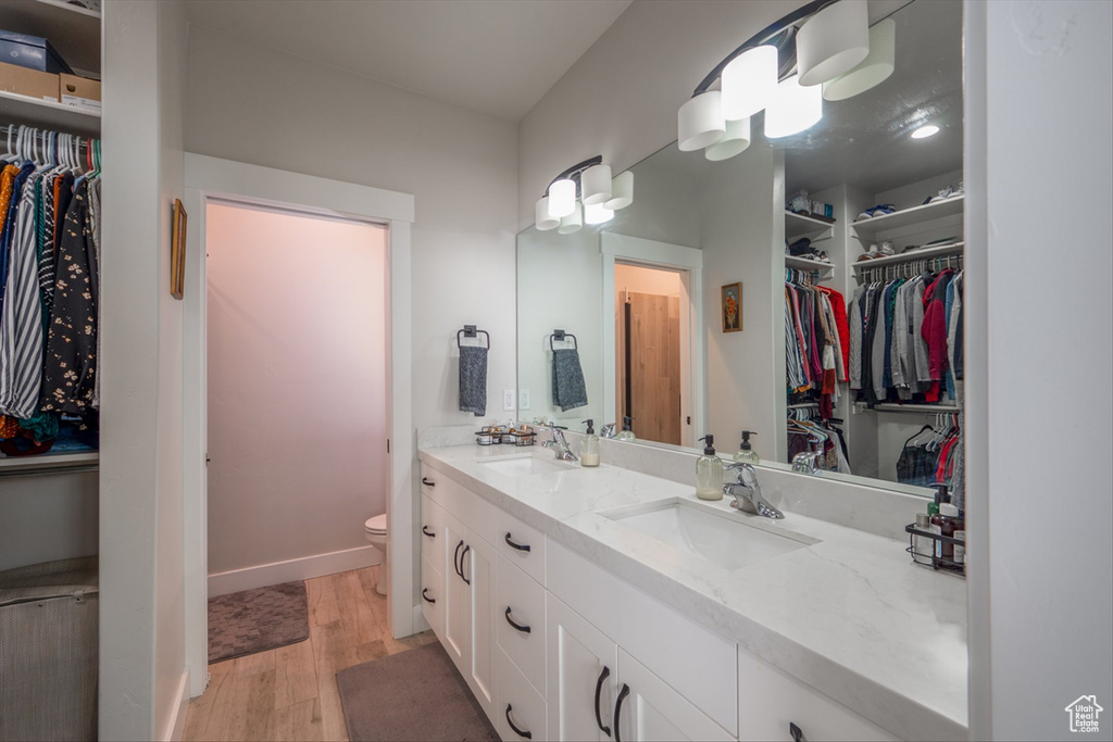 Full bathroom featuring toilet, wood finished floors, double vanity, and a sink
