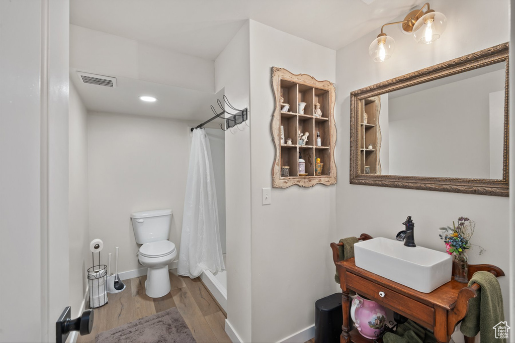 Bathroom with visible vents, toilet, a shower stall, and wood finished floors