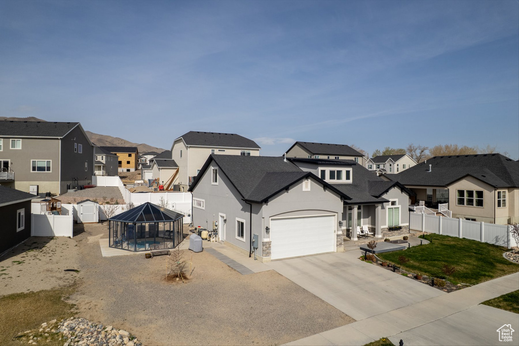 View of front facade featuring a residential view, stucco siding, driveway, a front lawn, and a fenced backyard