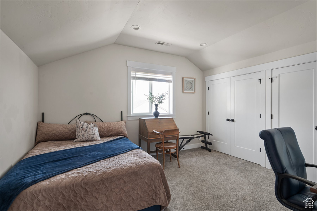 Bedroom with visible vents, carpet flooring, and vaulted ceiling