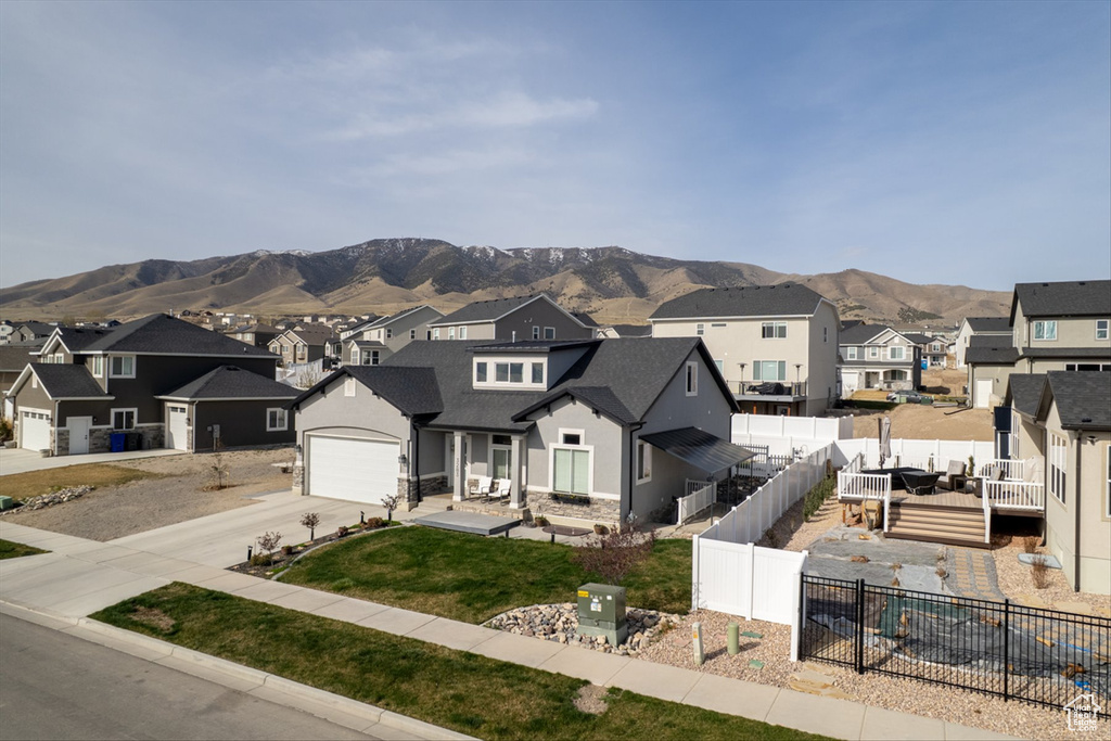 View of front of house with a residential view, stucco siding, driveway, a front yard, and a fenced backyard