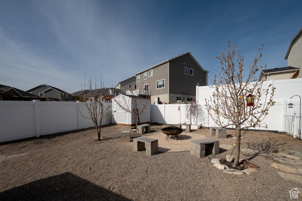 View of yard featuring a storage shed, an outbuilding, a fenced backyard, and a fire pit