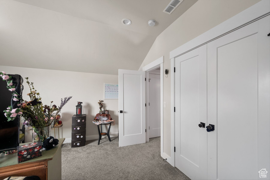 Interior space with visible vents, baseboards, vaulted ceiling, and carpet floors
