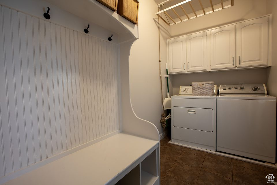 Washroom with cabinet space, independent washer and dryer, and dark tile patterned flooring