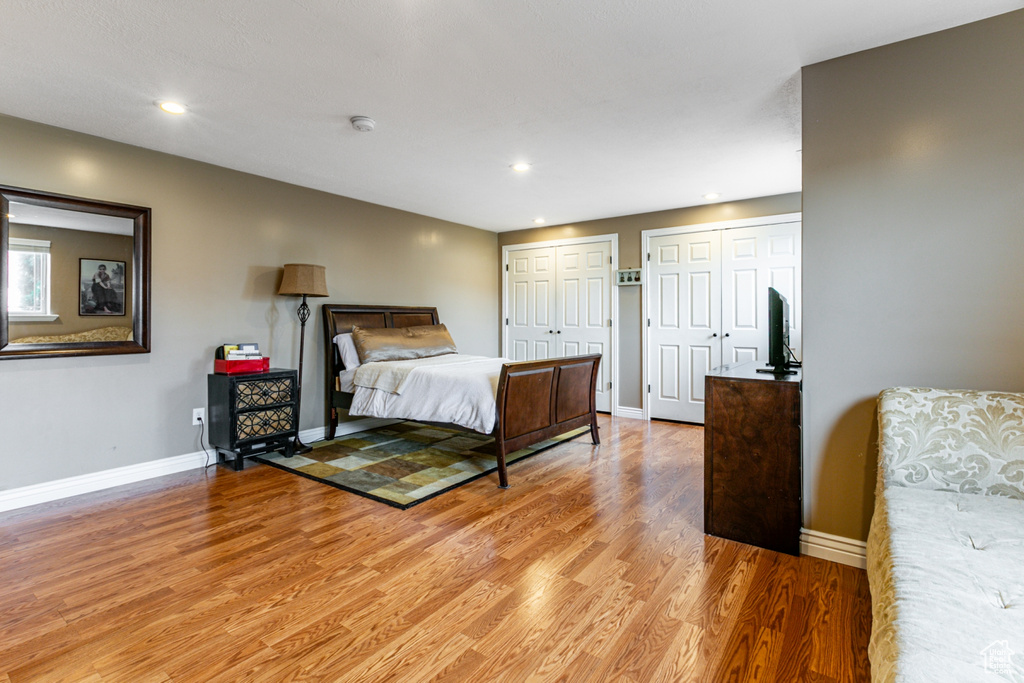 Bedroom featuring light wood-style floors, baseboards, two closets, and recessed lighting