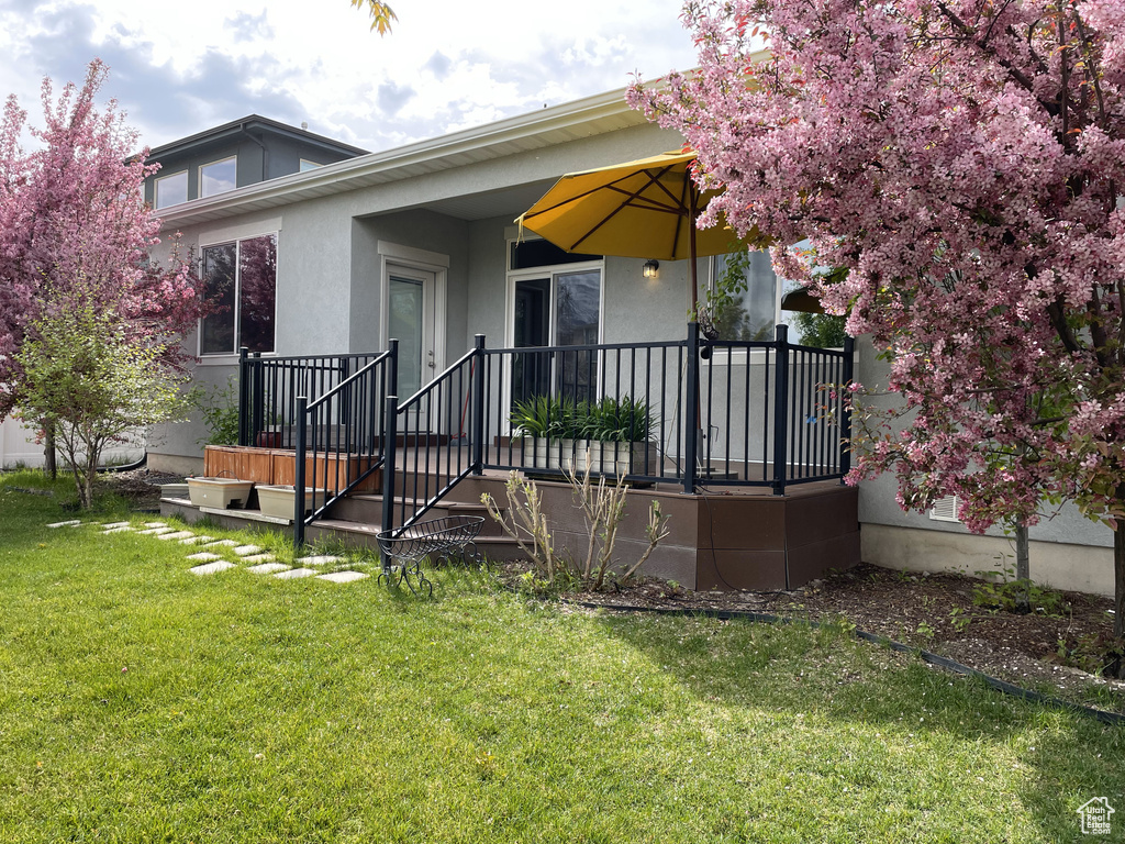Back of house with stucco siding and a yard