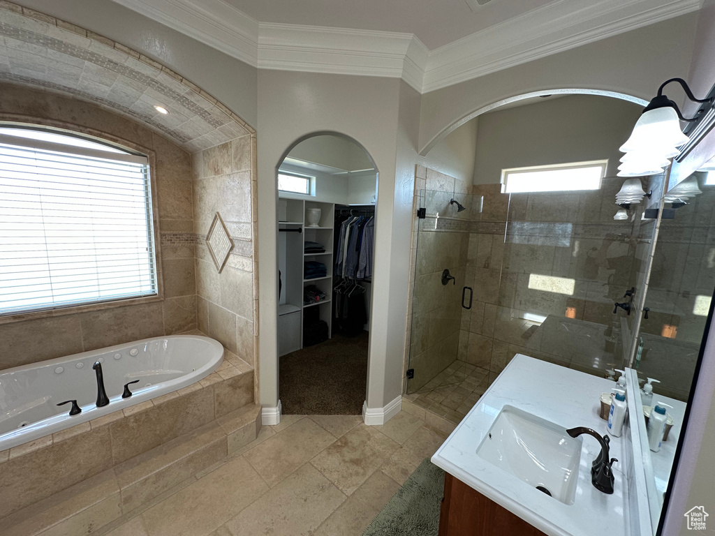 Bathroom featuring ornamental molding, a walk in closet, a jetted tub, vanity, and a stall shower