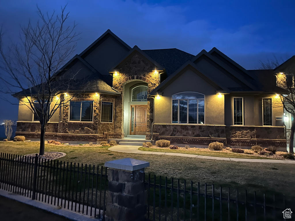 View of front of house with a fenced front yard, stone siding, and stucco siding