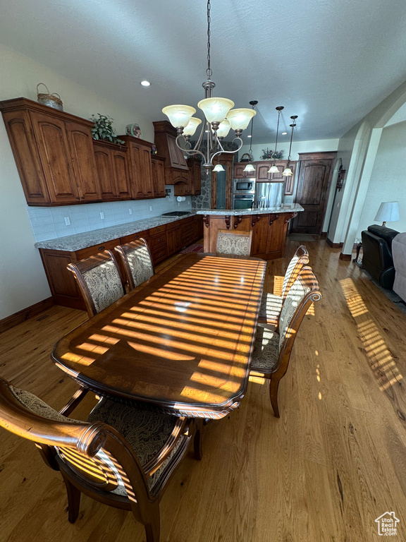 Dining room with a chandelier, baseboards, dark wood-style floors, and recessed lighting