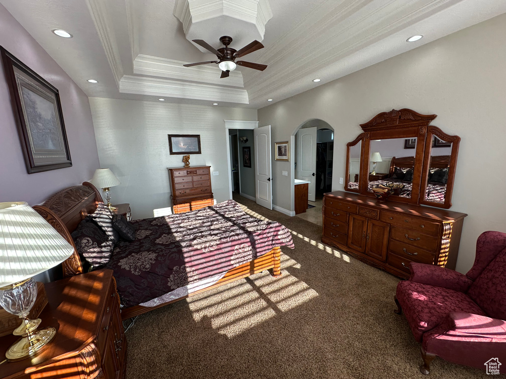 Bedroom featuring a raised ceiling, arched walkways, ornamental molding, carpet, and recessed lighting