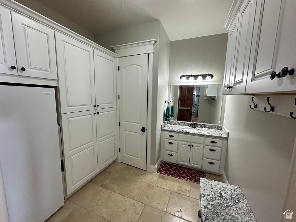 Bathroom with vanity, stone tile floors, and baseboards