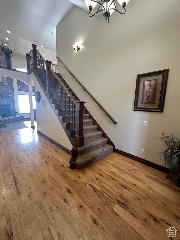 Staircase with a chandelier, arched walkways, baseboards, and hardwood / wood-style flooring