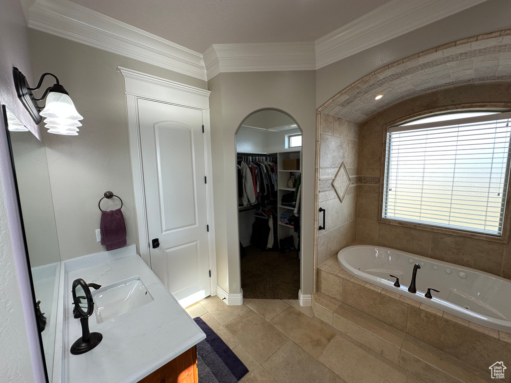 Bathroom with a whirlpool tub, vanity, tile patterned floors, crown molding, and a walk in closet